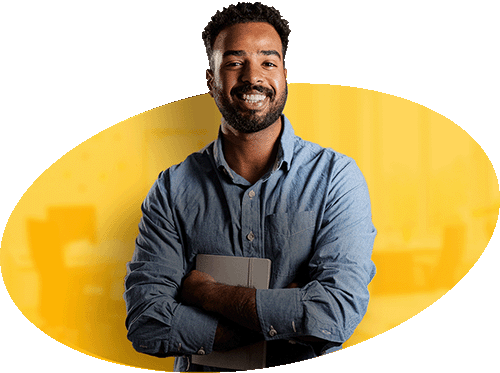 Homem sorridente e engajado, com barba e cabelo crespo, vestindo camisa jeans azul, segurando um tablet para apresentar ou consultar informações em um ambiente de escritório com fundo amarelo, representando a equipe de atendimento comercial consultiva da Alternativa Sistemas e a interação com suas soluções digitais.
