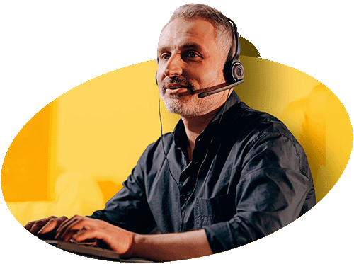 Profissional de atendimento e suporte da Alternativa Sistemas, com barba grisalha e headset com microfone, concentrado ao digitar em um teclado em um ambiente de escritório com fundo amarelo, simbolizando a excelência e o compromisso da equipe com o suporte técnico e comercial de suas soluções ERP para e-commerce.